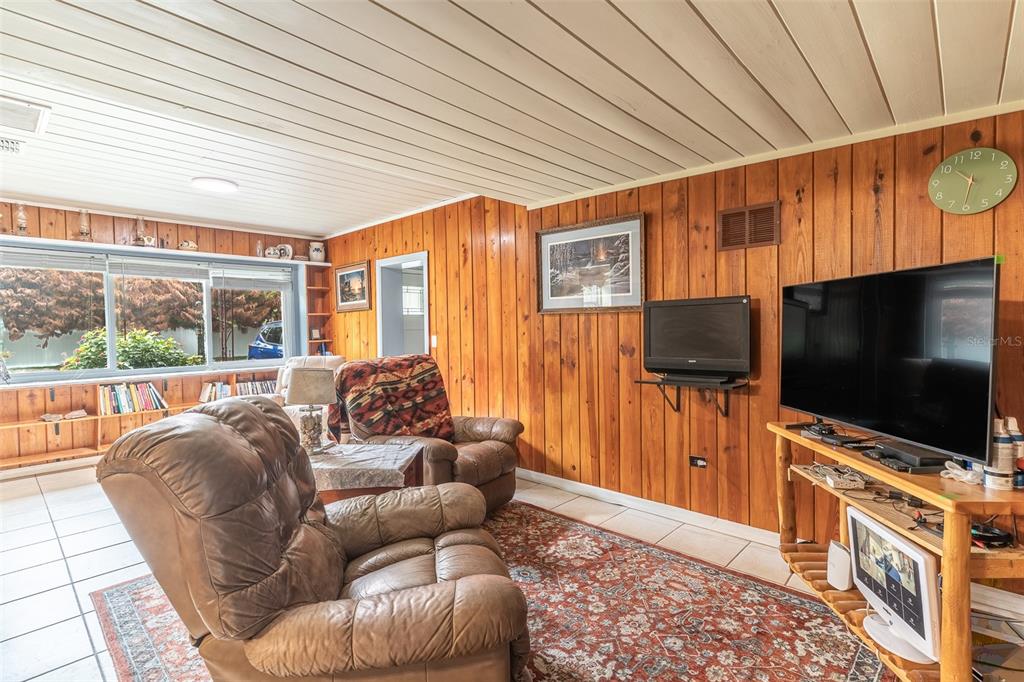 A living room features wood-paneled walls, tile flooring, two leather recliners, and a television — 1645 HUNTINGTON STREET, LAKELAND, FL