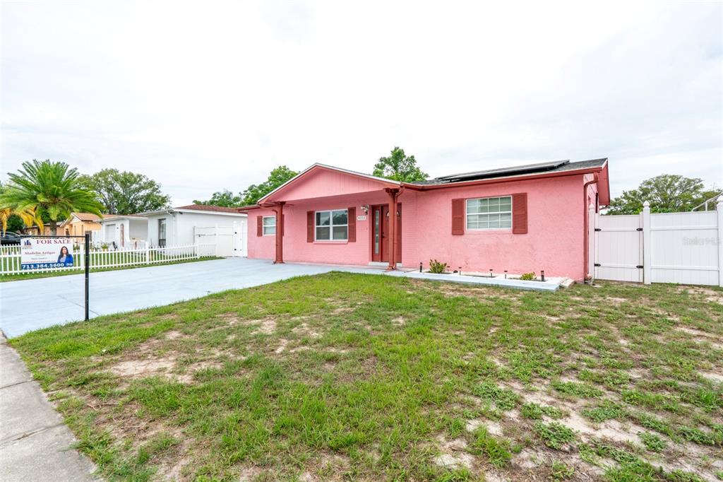 A single-story pink house with a white fence and a paved driveway — 8033 MANVEL DRIVE, PORT RICHEY, FL