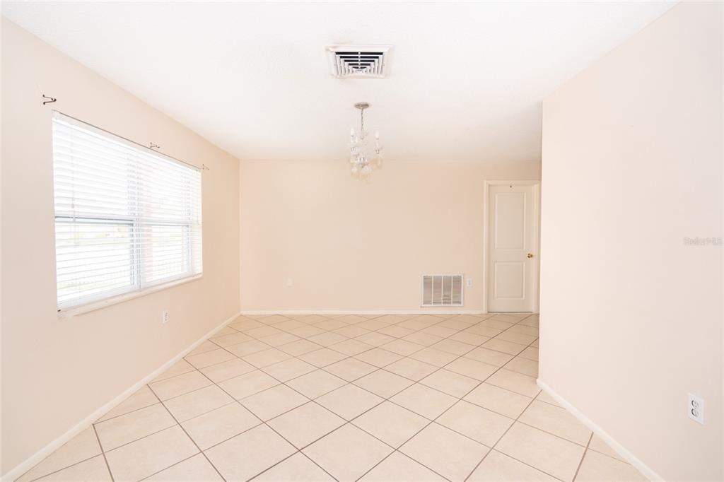 A dining room with beige walls, tile flooring, a window with blinds, and a chandelier — 8033 MANVEL DRIVE, PORT RICHEY, FL
