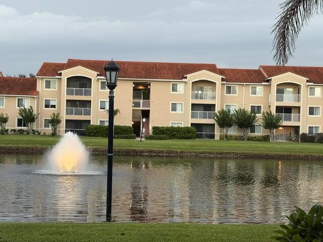 A multi-story apartment building with a red tile roof overlooks a pond with a fountain — 1590 S 42nd Circle S # 308, Vero Beach FL 32967, VERO BEACH, FL