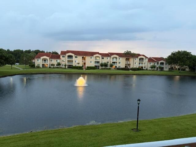 A multi-story apartment complex sits behind a pond with a central water fountain — 1590 S 42nd Circle S # 308, Vero Beach FL 32967, VERO BEACH, FL