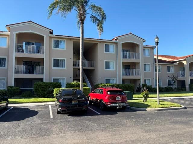 A multi-story apartment building features beige stucco walls, white railings, and a palm tree — 1590 S 42nd Circle S # 308, Vero Beach FL 32967, VERO BEACH, FL