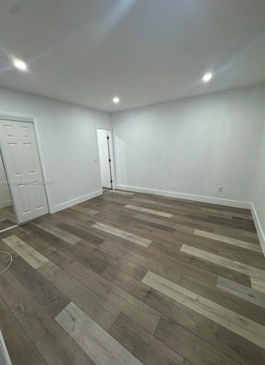 An empty room features white walls, recessed lighting, and wood-look flooring — 5860 NW 193rd St # 1, Hialeah FL 33015, HIALEAH, FL