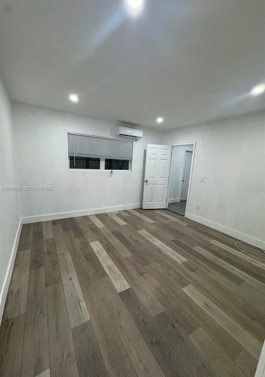 A room with white walls, wood-look flooring, a window with blinds, and a mini-split unit — 5860 NW 193rd St # 1, Hialeah FL 33015, HIALEAH, FL