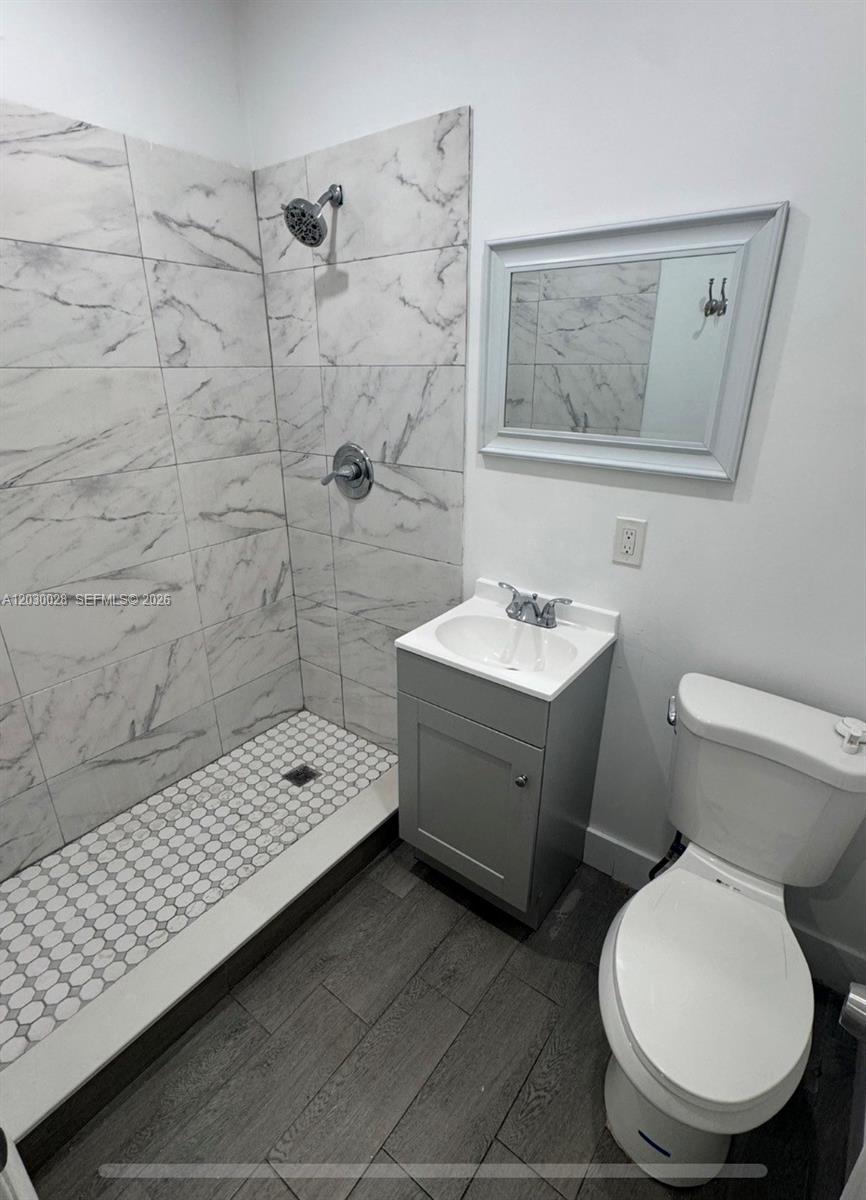 A small bathroom features a walk-in shower with marble-look tiles, a vanity, and a toilet — 5860 NW 193rd St # 1, Hialeah FL 33015, HIALEAH, FL