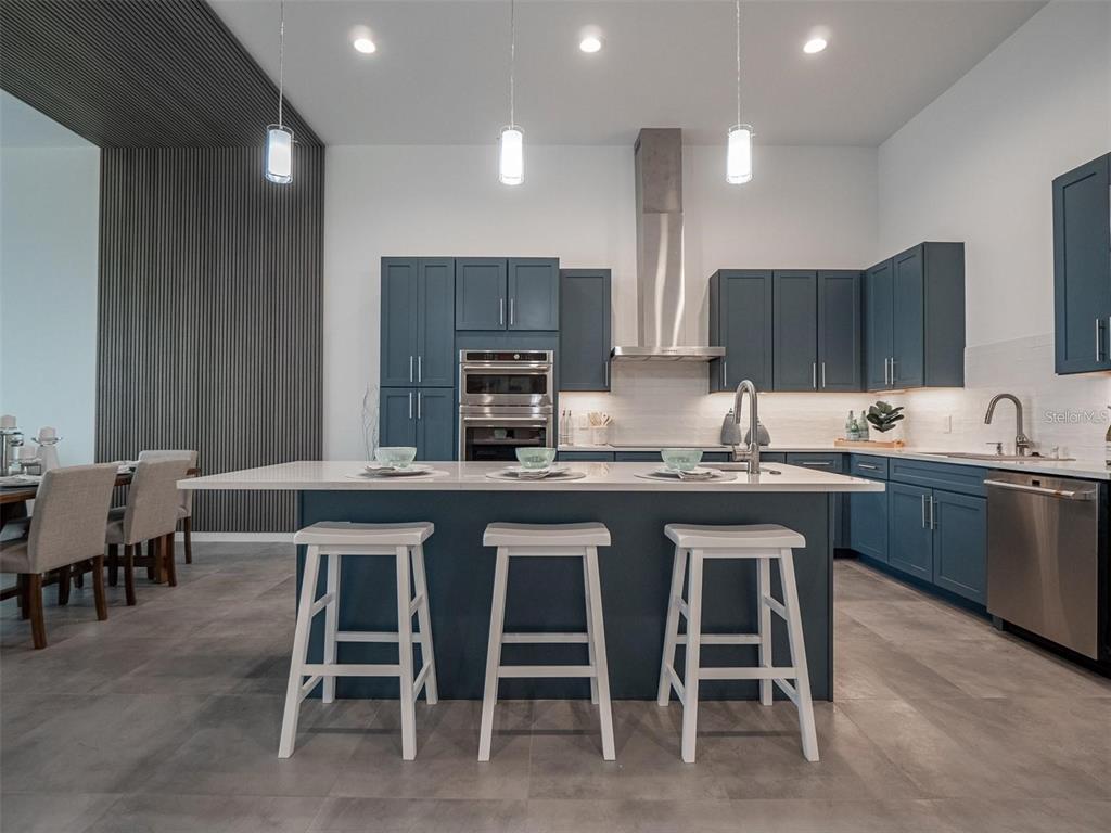 A modern kitchen features blue cabinetry, a white quartz island, and three white bar stools — 920 N OSCEOLA AVENUE UNIT 801, CLEARWATER, FL