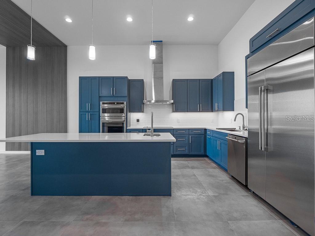 A modern kitchen features blue cabinetry, stainless steel appliances, and a large white island — 920 N OSCEOLA AVENUE UNIT 801, CLEARWATER, FL