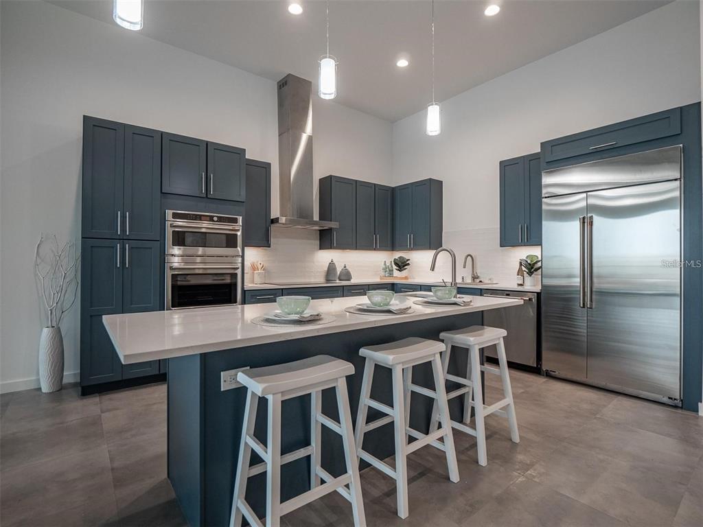 A modern kitchen features blue cabinetry, a white quartz island, and stainless steel appliances — 920 N OSCEOLA AVENUE UNIT 801, CLEARWATER, FL