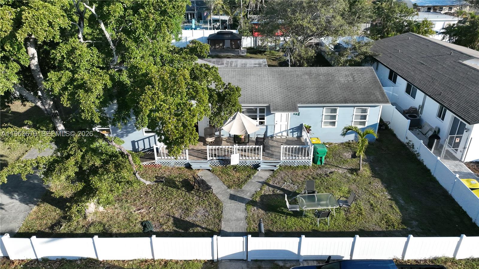 An aerial view shows a light blue house with a deck, patio furniture, and yard — 228 SW 8th St, Dania Beach FL 33004, DANIA BEACH, FL
