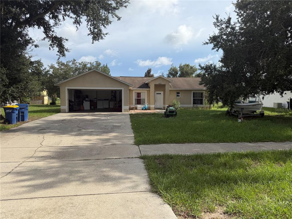 A single-story house with a two-car garage, a concrete driveway, and a front lawn — 260 BOCA CIEGA ROAD, MASCOTTE, FL