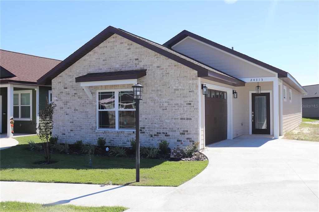 A single-story house with a brick facade, a garage, and a concrete driveway — 24313 SW 17TH LANE, NEWBERRY, FL
