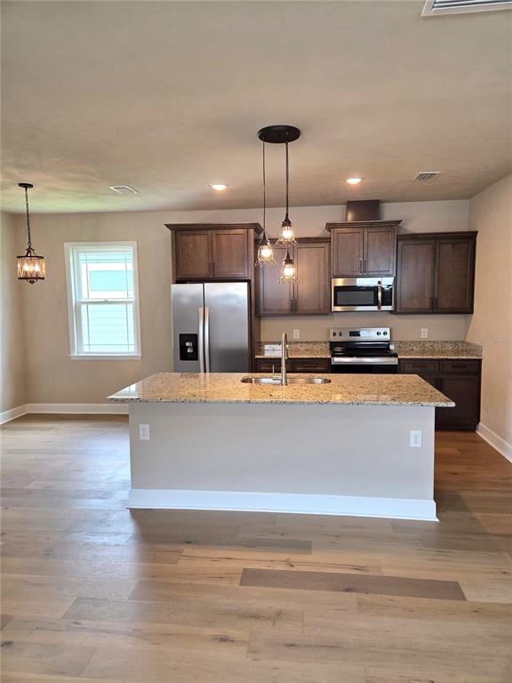 A kitchen features dark wood cabinets, granite countertops, a center island, and light wood flooring — 24313 SW 17TH LANE, NEWBERRY, FL