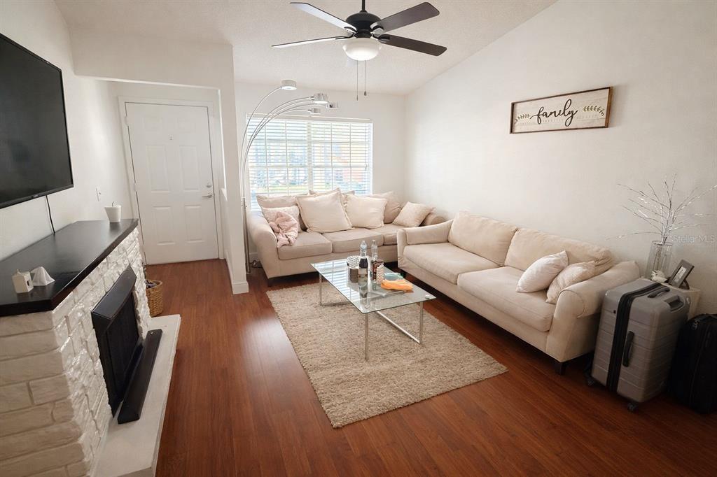 A living room features two beige sofas, a glass coffee table, and a white fireplace — 5473 LAKE MARGARET DRIVE UNIT G, ORLANDO, FL