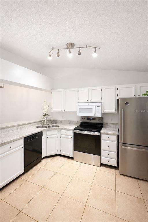 A kitchen features white cabinets, stainless steel appliances, and light-colored tile flooring — 5473 LAKE MARGARET DRIVE UNIT G, ORLANDO, FL
