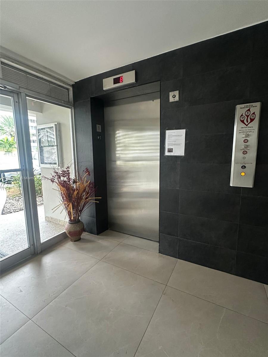 A stainless steel elevator sits in a lobby with dark tiled walls and light flooring — 1780 NE 191st St # 2, Miami FL 33179, MIAMI, FL