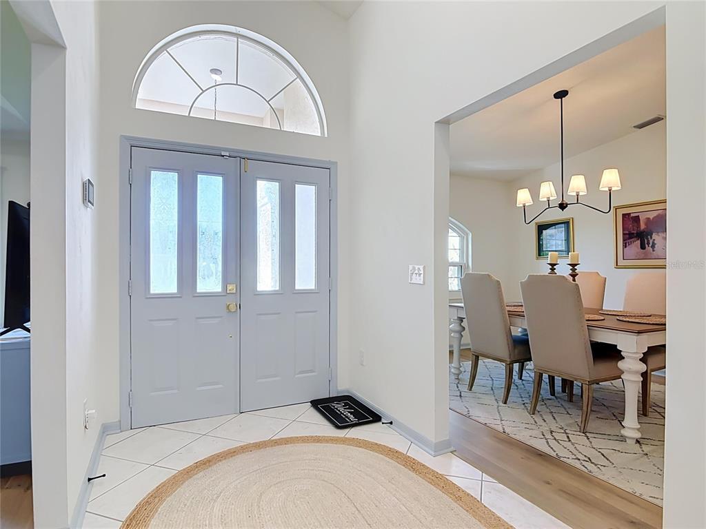 A foyer with a light blue double door, arched window, and adjacent dining room — 1 EASTMOOR LANE, PALM COAST, FL