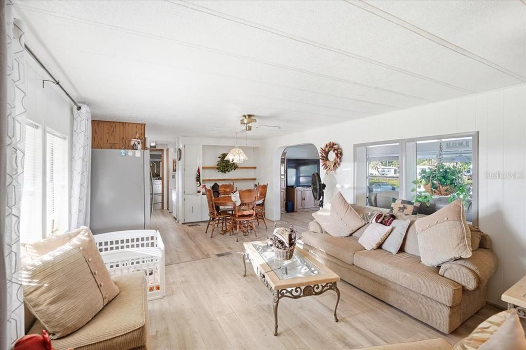 An open-concept living and dining area features light wood-look flooring and white paneled walls — 928 S SHAD TERRACE, INVERNESS, FL