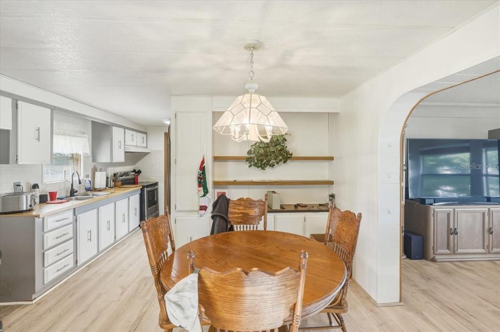 A kitchen and dining area with white cabinets, wood-look flooring, and a round wooden table — 928 S SHAD TERRACE, INVERNESS, FL
