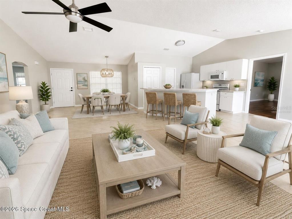 This open-concept living and dining area features tile flooring, neutral walls, and a kitchen island — 7423 BUMELIA DRIVE, COCOA, FL