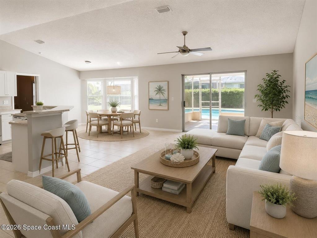 An open-concept living and dining area features tile flooring, a kitchen island, and sliding glass doors — 7423 BUMELIA DRIVE, COCOA, FL