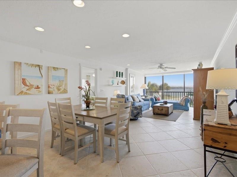 An open-concept living and dining area with tile floors, a balcony, and water views — 8911 MIDNIGHT PASS ROAD UNIT 208, SARASOTA, FL