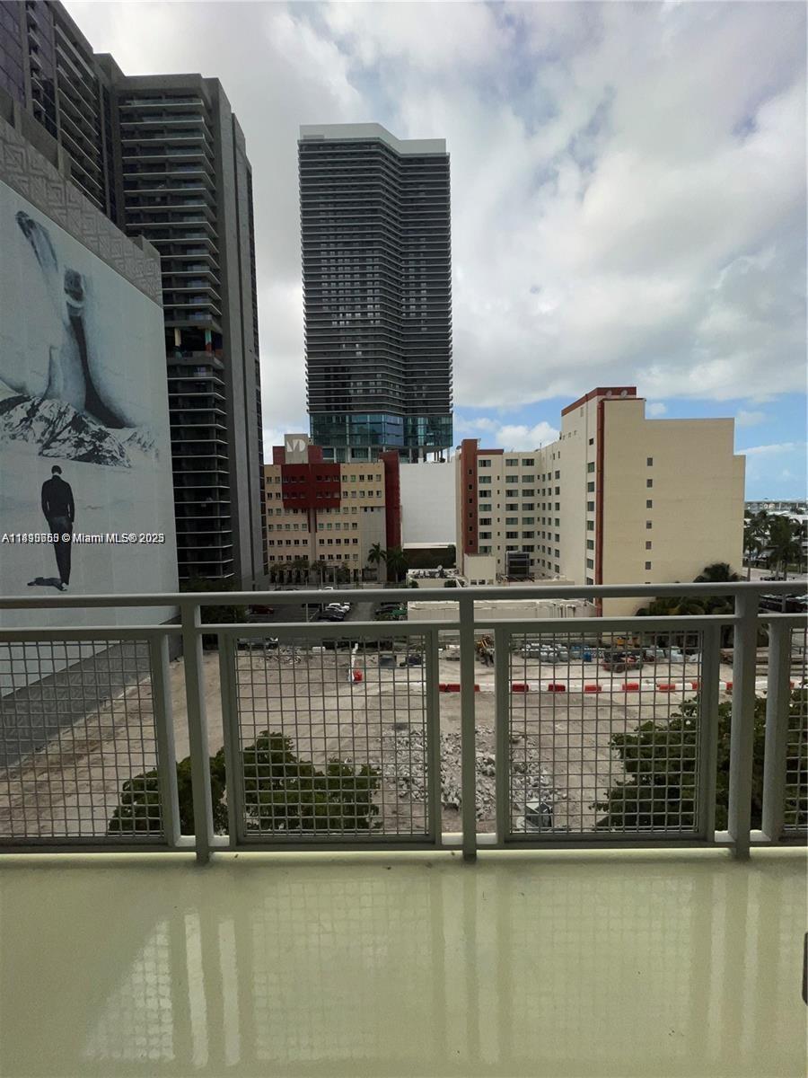 A balcony overlooks a vacant lot surrounded by several high-rise buildings under a cloudy sky — 244 Biscayne Blvd # 643, Miami FL 33132, MIAMI, FL