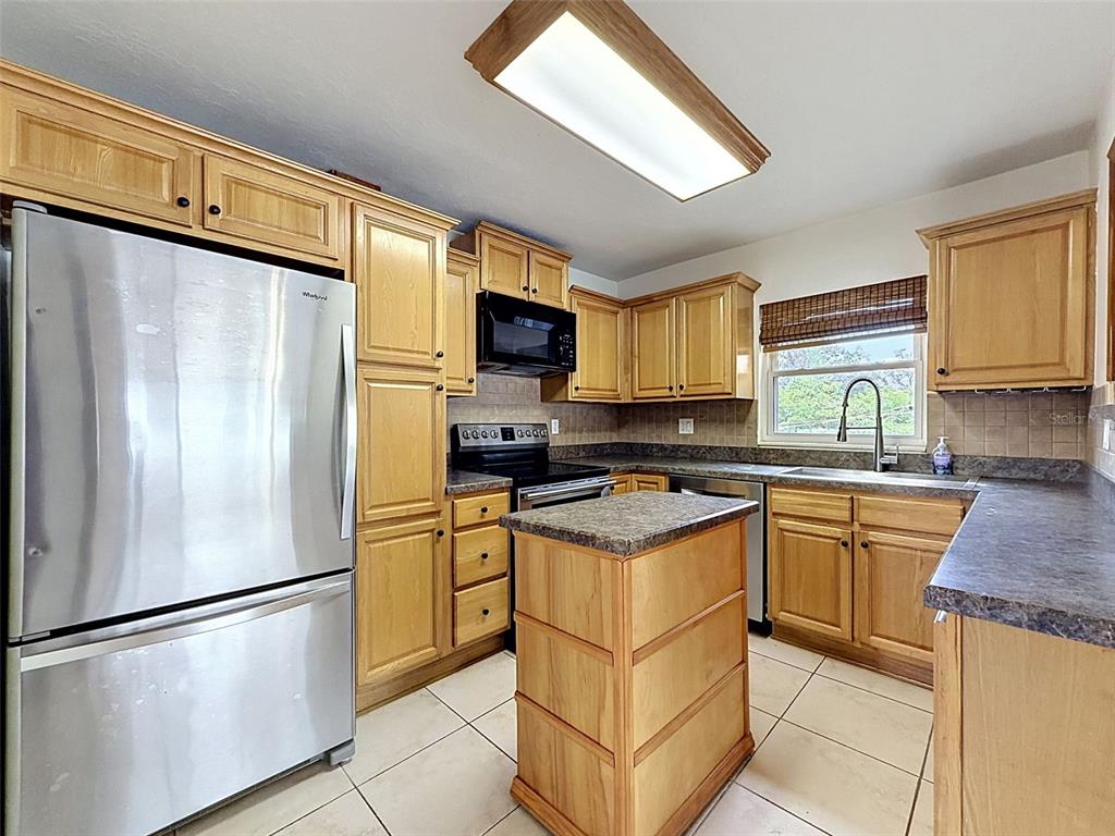 A kitchen with light wood cabinets, stainless steel appliances, a small island, and tile flooring — 2518 W NORTH STREET, TAMPA, FL