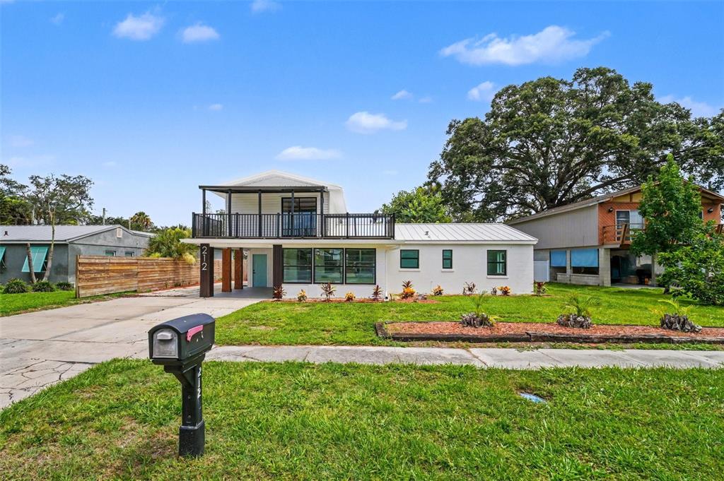 A two-story white house with a large upper balcony and a front driveway — 212 COQUINA DRIVE, COCOA, FL