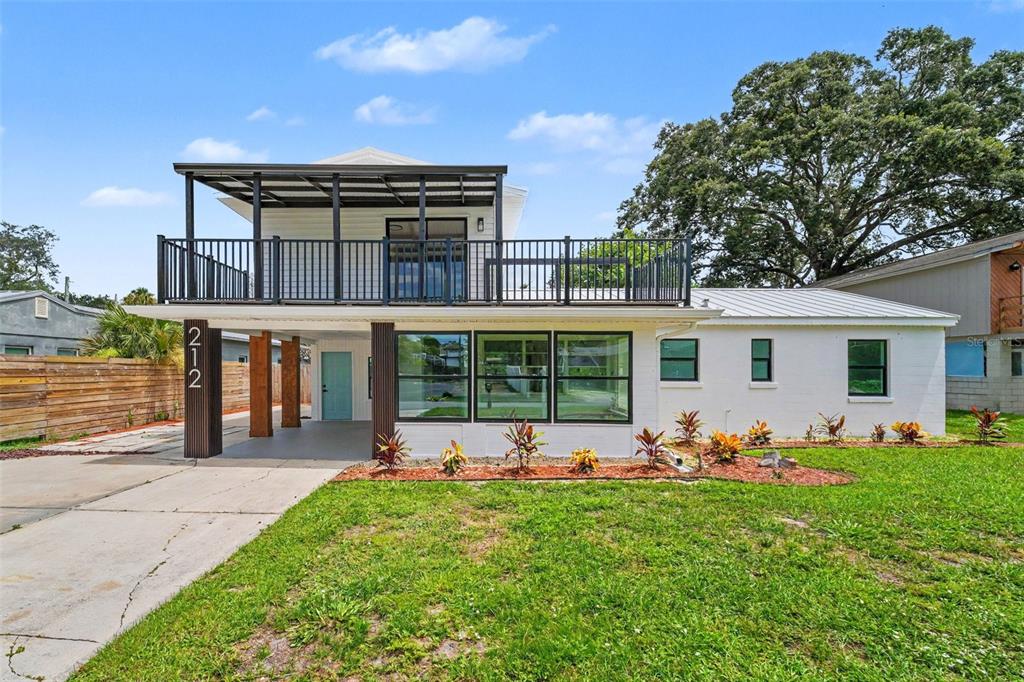 A two-story house with a white exterior, a covered carport, and an upper-level balcony — 212 COQUINA DRIVE, COCOA, FL