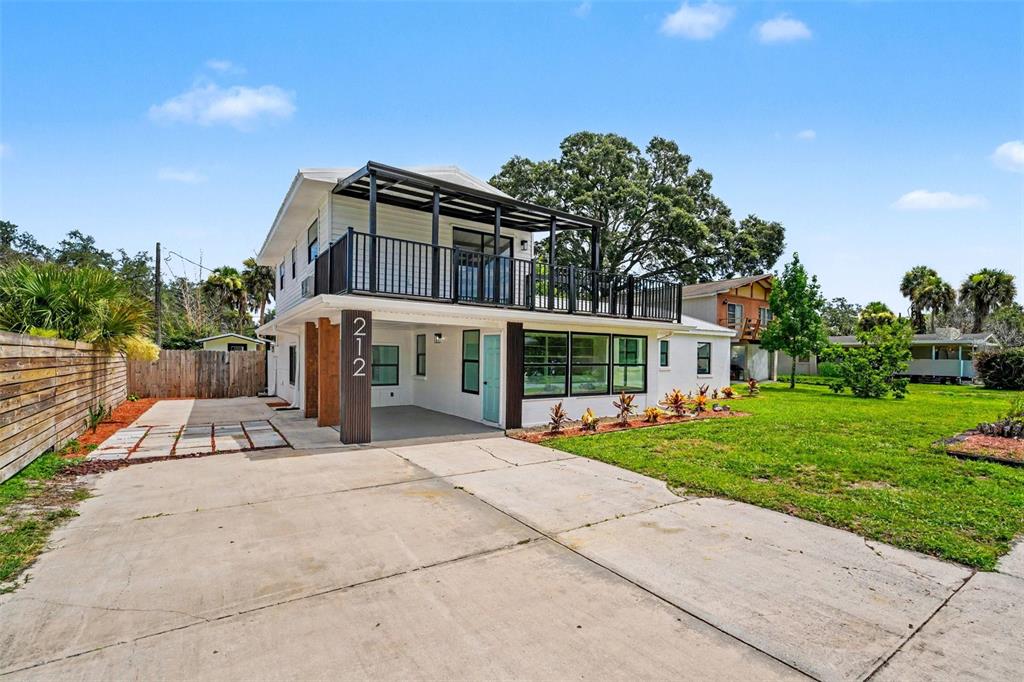 A two-story house with a white exterior, a covered carport, and a second-floor balcony — 212 COQUINA DRIVE, COCOA, FL
