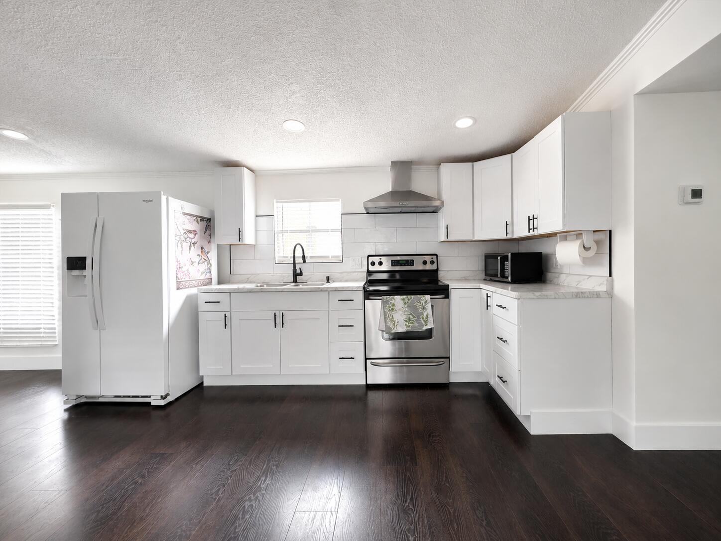 A kitchen features white cabinets, stainless steel appliances, a subway tile backsplash, and dark flooring — 182 Plantation Boulevard, FL 33467, FL