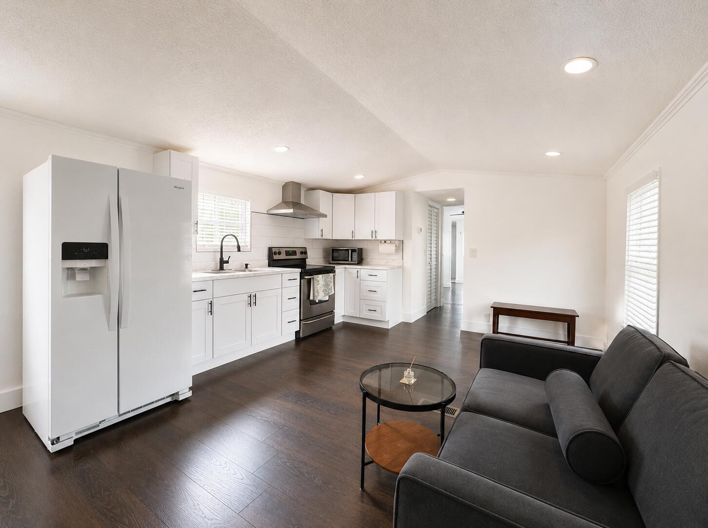 A kitchen with white cabinets and stainless steel appliances opens into a living area — 182 Plantation Boulevard, FL 33467, FL