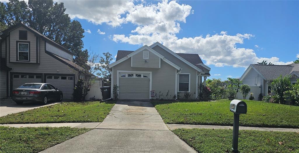 A beige single-story house with a garage and a concrete driveway under a blue sky — 9906 SURREY RIDGE ROAD, ORLANDO, FL