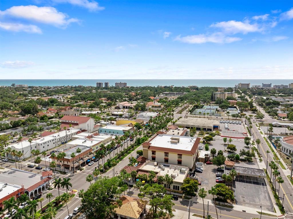An aerial view shows a coastal town with buildings, palm trees, and the ocean beyond — 1543 WATERFORD DRIVE, VENICE, FL