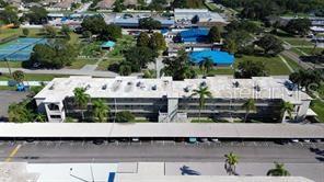 An aerial view shows a multi-story apartment building with a covered parking area in front — 970 VIRGINIA STREET UNIT 103, DUNEDIN, FL