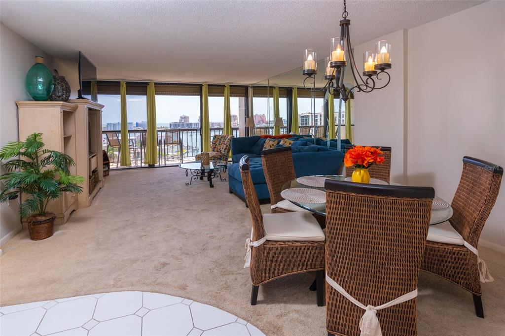 A dining area with wicker chairs and a living room featuring a blue sectional sofa — 400 ISLAND WAY UNIT 1004, CLEARWATER BEACH, FL