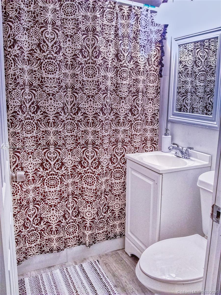 A small bathroom features a patterned shower curtain, a white vanity, and a toilet — 142 NE 56th St # c, Miami FL 33137, MIAMI, FL