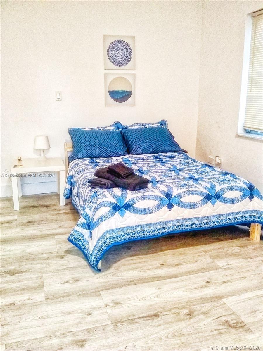 A bedroom features a bed with a blue and white patterned quilt and wood-look flooring — 142 NE 56th St # c, Miami FL 33137, MIAMI, FL