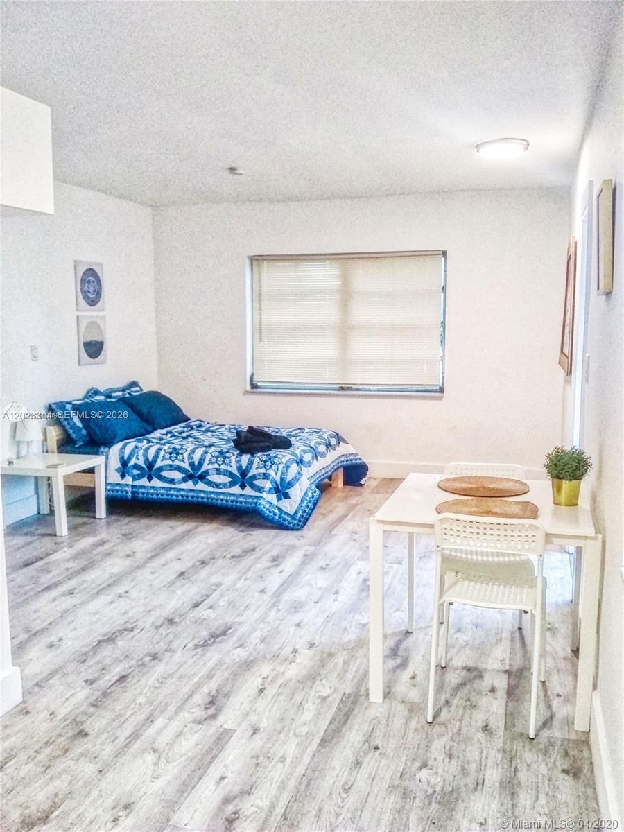 A bedroom with a bed, a small dining table, and light wood-look flooring — 142 NE 56th St # c, Miami FL 33137, MIAMI, FL
