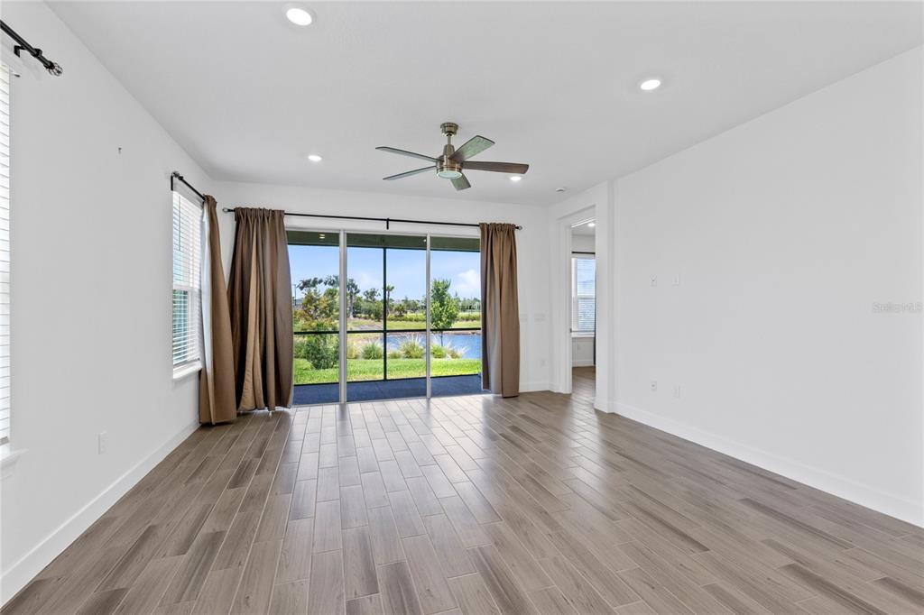 A bright living room features wood-look tile flooring, a ceiling fan, and sliding glass doors — 5338 SPOONFLOWER COURT, ST CLOUD, FL