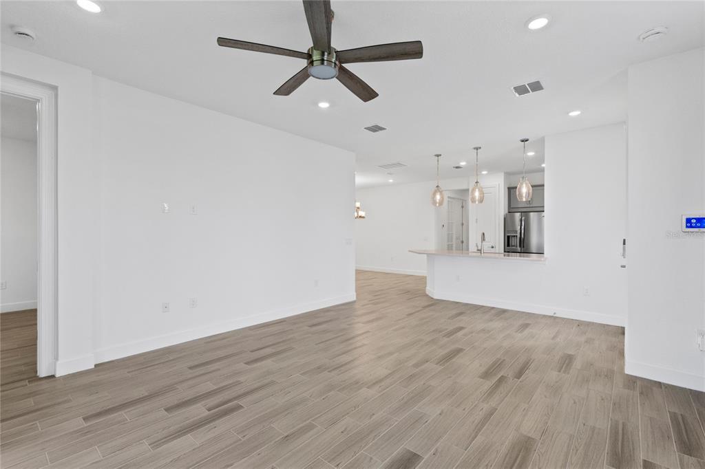 An open-concept living area features wood-look tile flooring, a ceiling fan, and a kitchen island — 5338 SPOONFLOWER COURT, ST CLOUD, FL