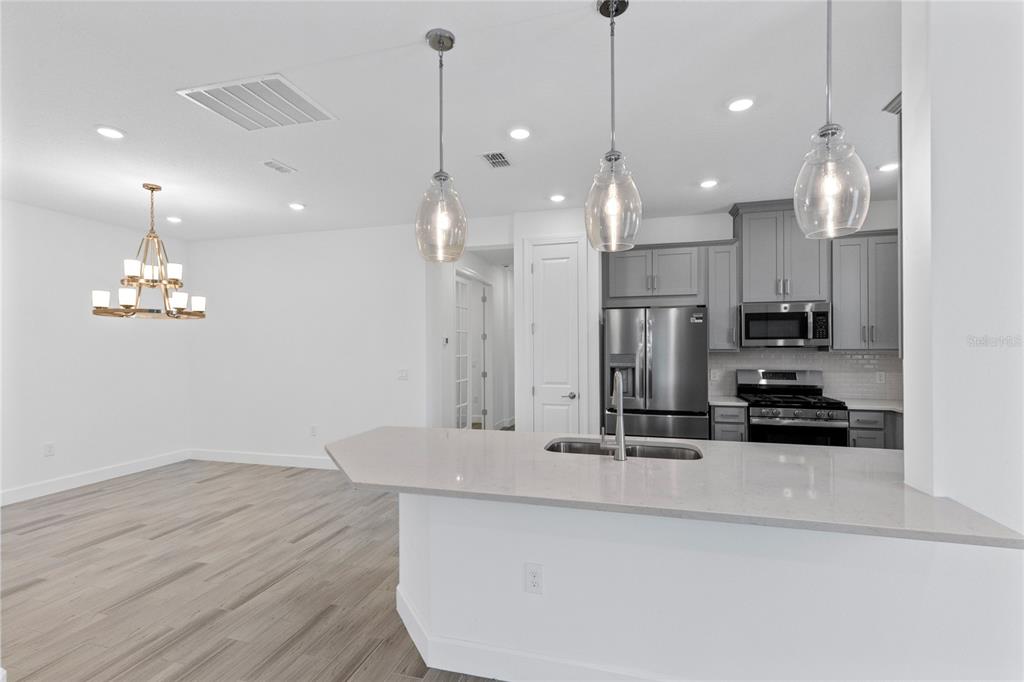 A kitchen with gray cabinets, stainless steel appliances, and a quartz-topped island with pendant lights — 5338 SPOONFLOWER COURT, ST CLOUD, FL