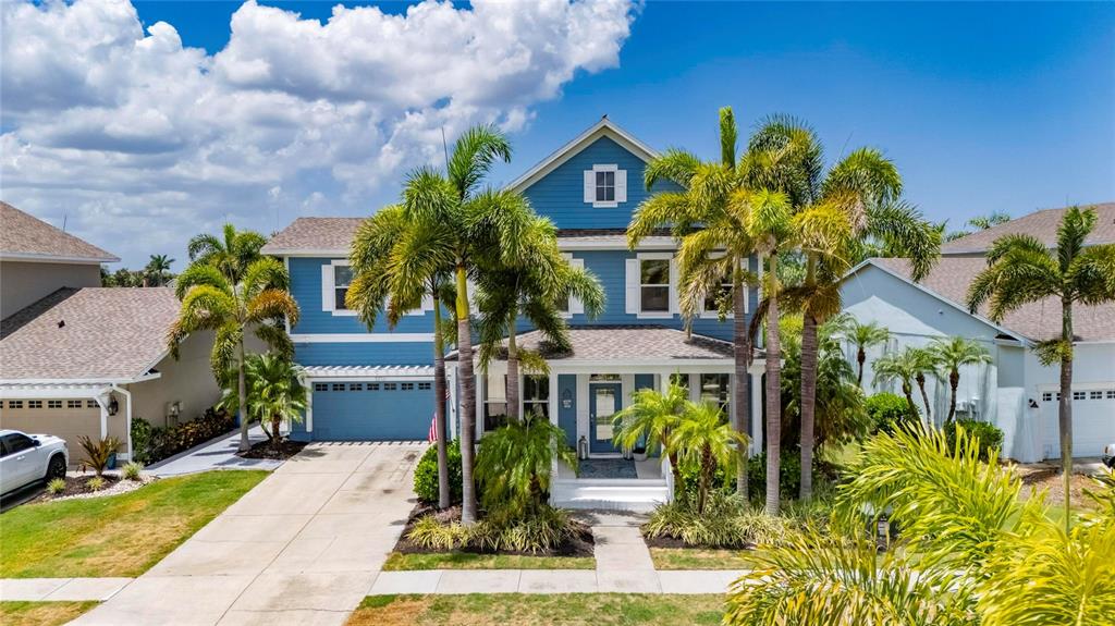A two-story blue house with a front porch, palm trees, and a concrete driveway — 5216 POINT HARBOR LANE, APOLLO BEACH, FL