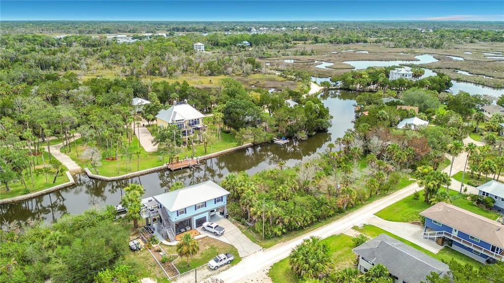 An aerial view shows houses along a canal surrounded by lush trees and marshland — 12073 W GULF BREEZE COURT, CRYSTAL RIVER, FL