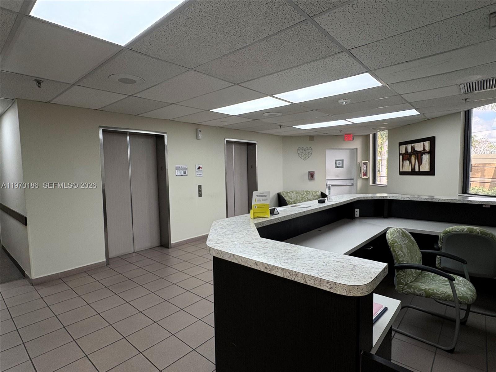 A reception area features a large L-shaped desk, two elevators, and a tiled floor — 2100 W 76th St # 206, Hialeah FL 33016, HIALEAH, FL