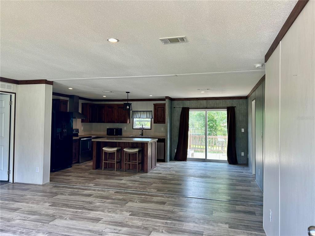 An open-concept kitchen and dining area features dark wood cabinets, a center island, and flooring — 11231 NE 60TH STREET, BRONSON, FL