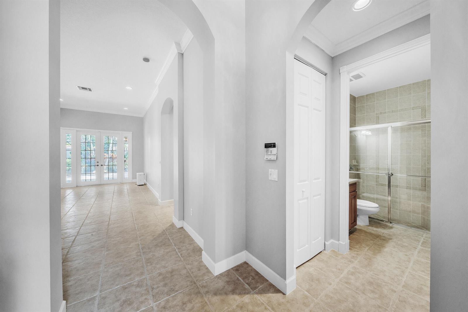A hallway with tile flooring leads to a glass-enclosed shower and a set of French doors — 6581 Southport Drive, Boynton Beach FL 33472, BOYNTON BEACH, FL