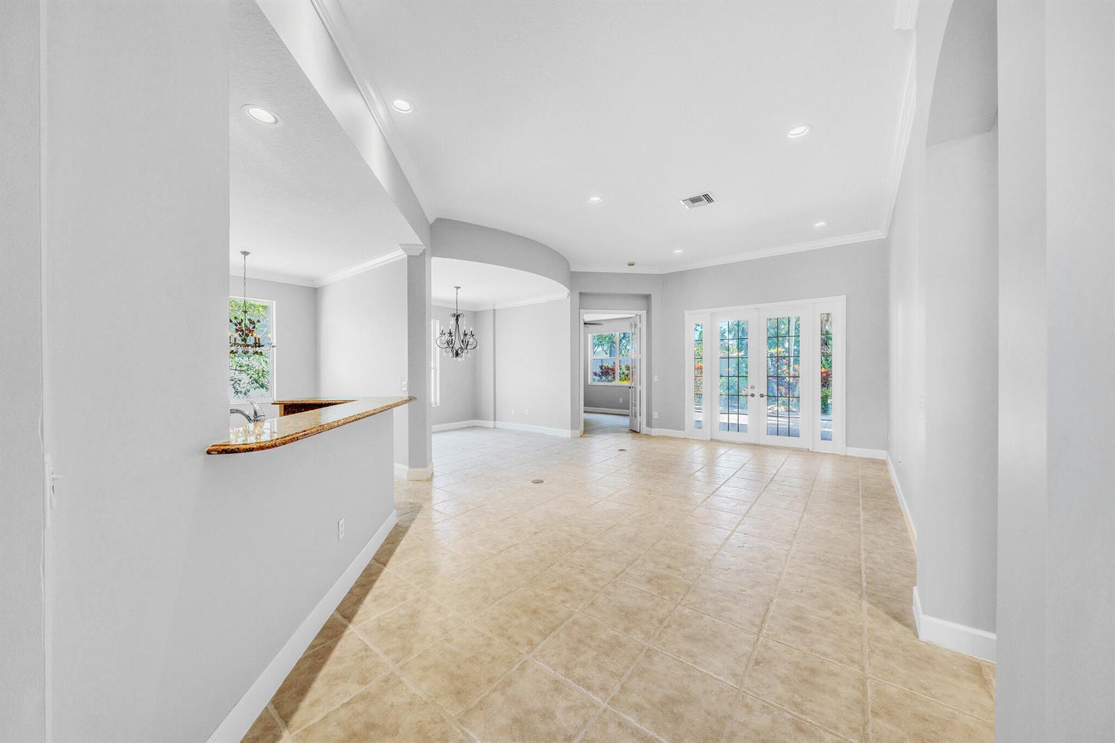 An open-concept living area features light tile flooring, a granite breakfast bar, and glass doors — 6581 Southport Drive, Boynton Beach FL 33472, BOYNTON BEACH, FL