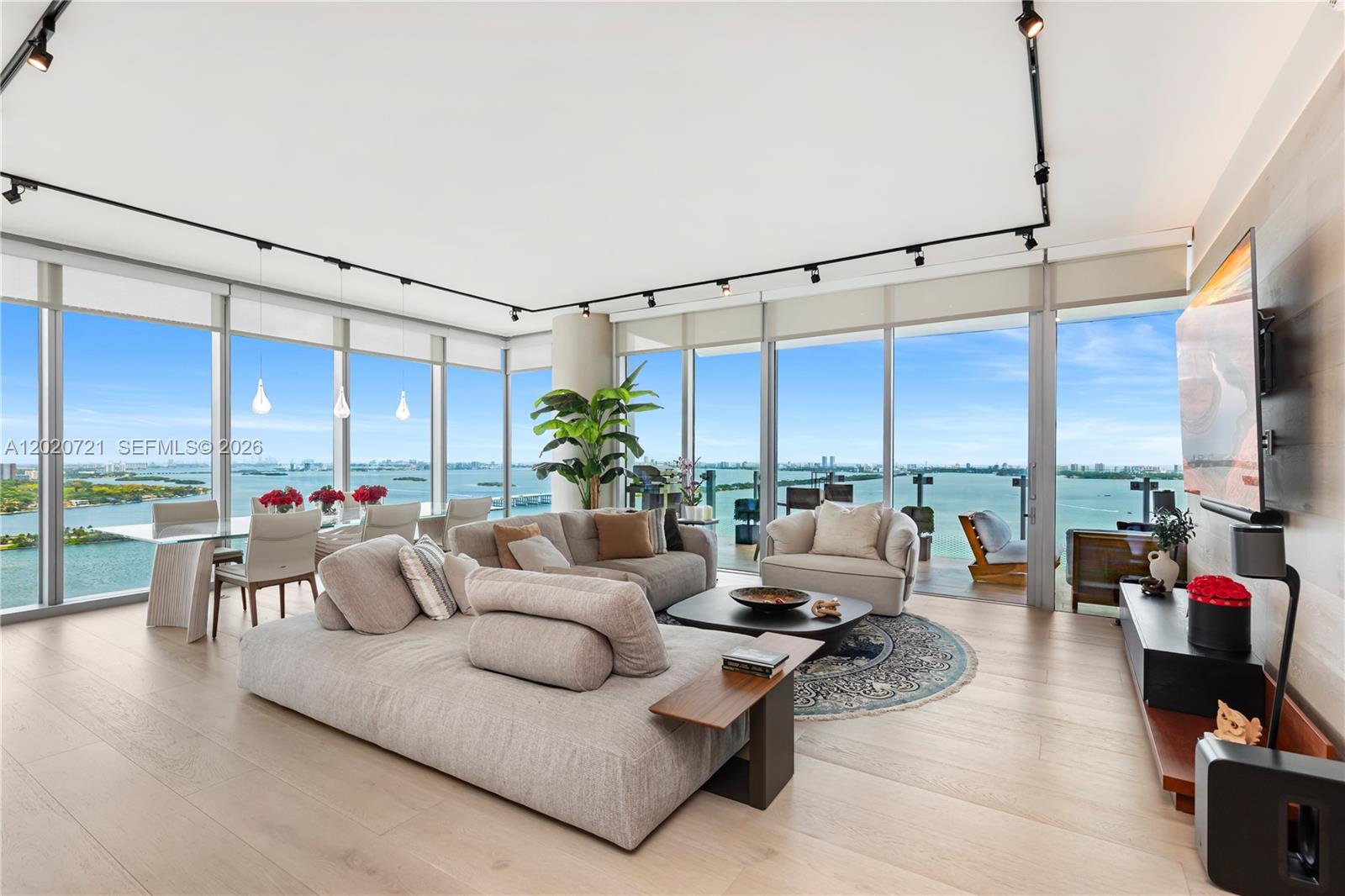 A modern living and dining area features floor-to-ceiling windows overlooking a bay — 700 NE 26th Ter # 2901, Miami FL 33137, MIAMI, FL