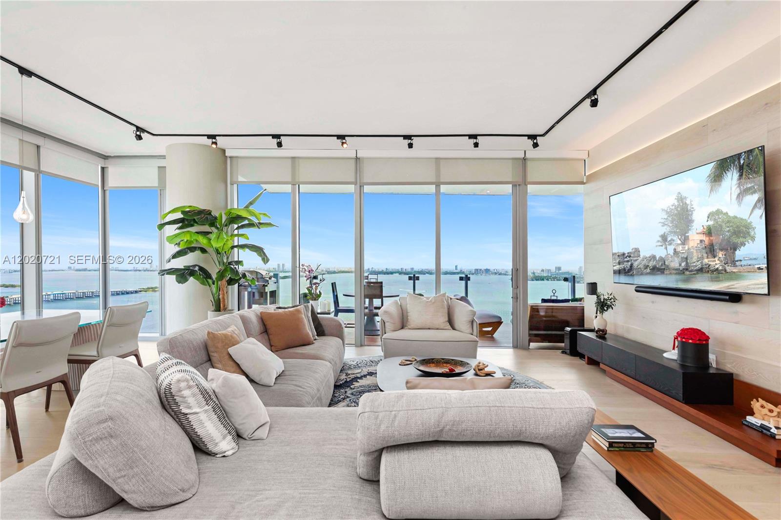 A modern living room features a large sectional sofa, floor-to-ceiling windows, and a waterfront view — 700 NE 26th Ter # 2901, Miami FL 33137, MIAMI, FL